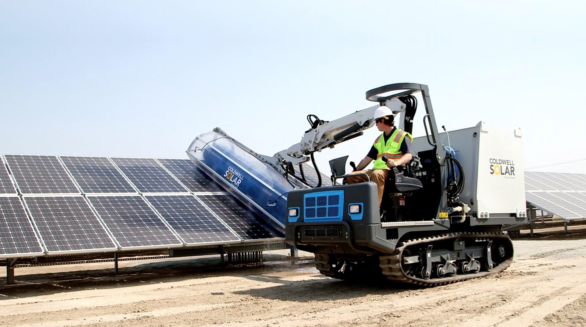 Coldwell Solar machine cleaning a row of ground-mounted solar panels on California agricultural land.