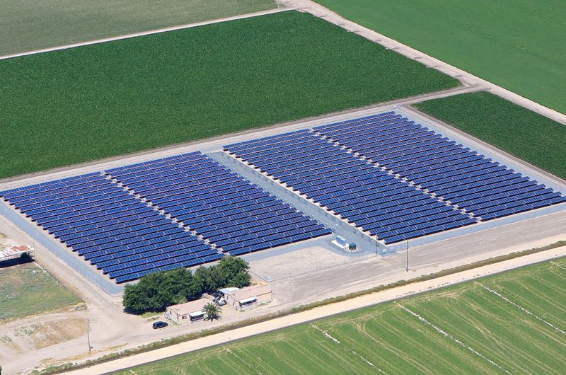 Large solar farm on California agricultural land bordered on all sides by green crop land.
