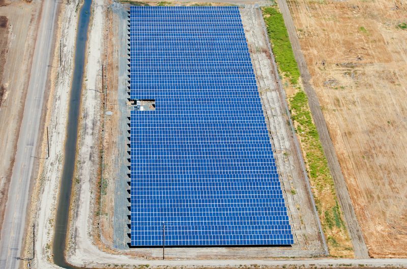 Aerial view of a small solar panel installation on a California dairy farm surrounded by plowed farm land.
