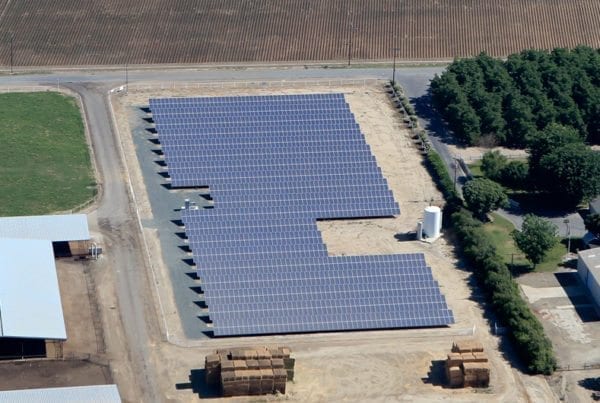 Aerial view of solar panels in a small solar farm on agricultural land in California.