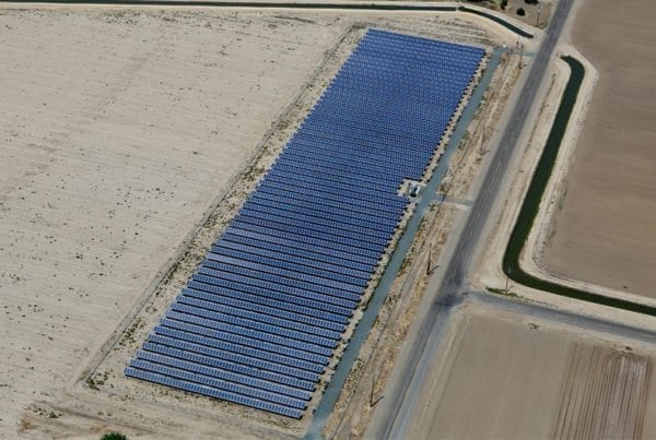 Aerial view of rows of solar panels in a solar installation on California agricultural land surrounded by plowed fields.