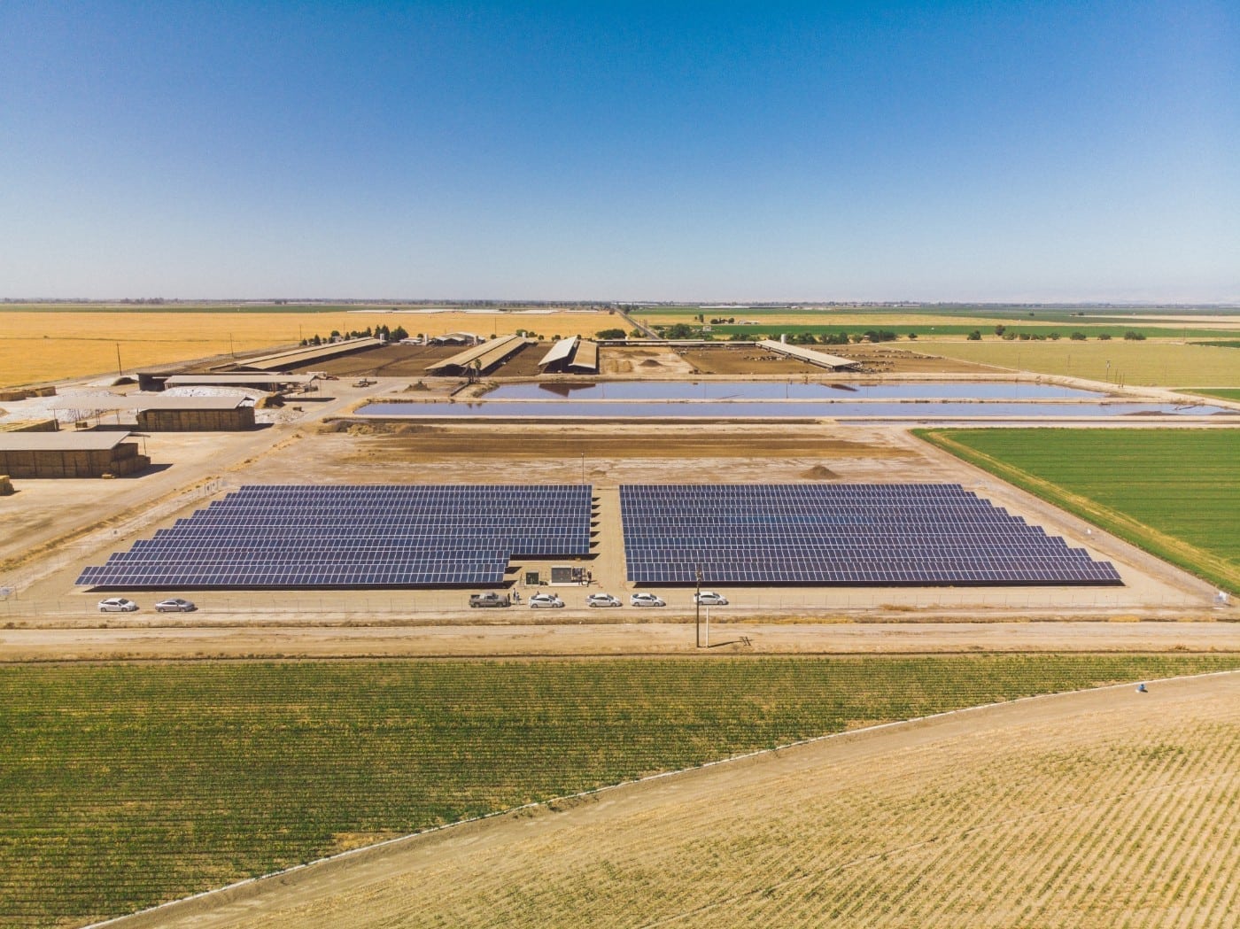 Aerial view of the solar installation at Rockshar Dairy in California surrounded by crop land, livestock pens and two water retention ponds.