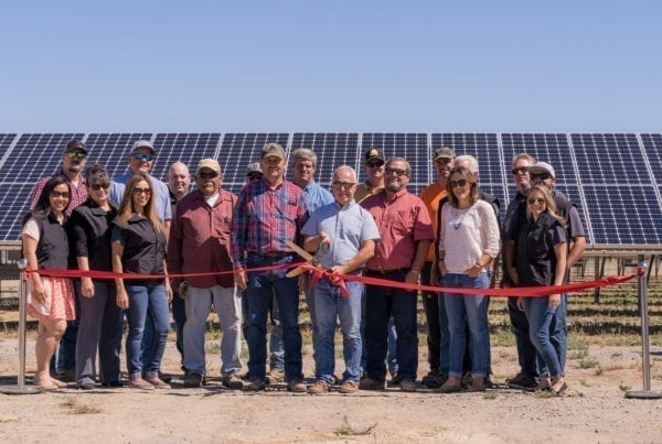 A group of employees from the Sycamore Mutual Water Company in Colusa, California standing at the ribbon cutting ceremony in front of their new solar panels.