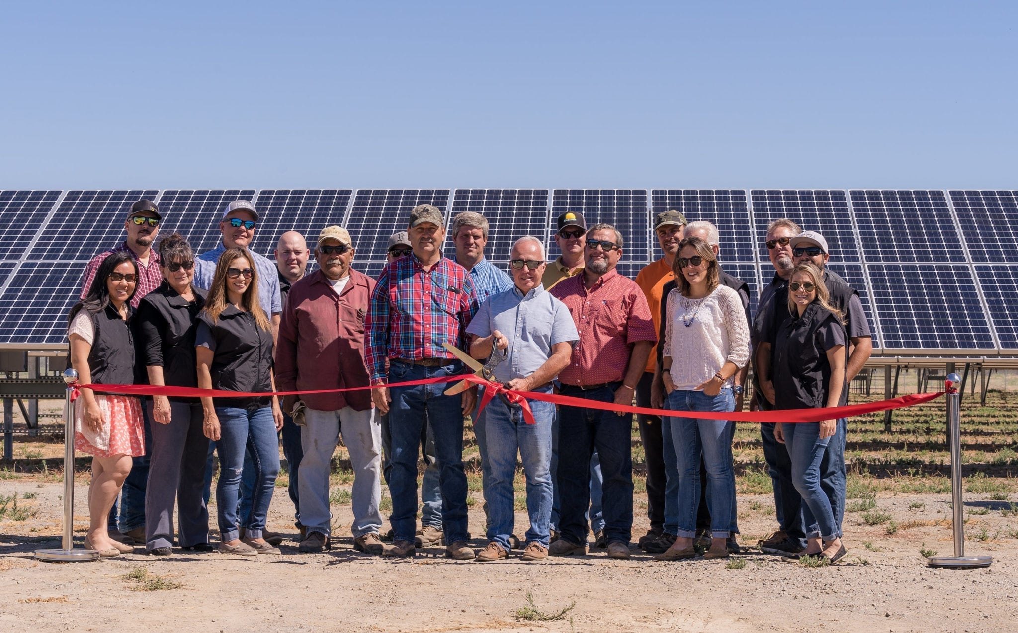 A group of employees from the Sycamore Mutual Water Company in Colusa, California standing at the ribbon cutting ceremony in front of their new solar panels.