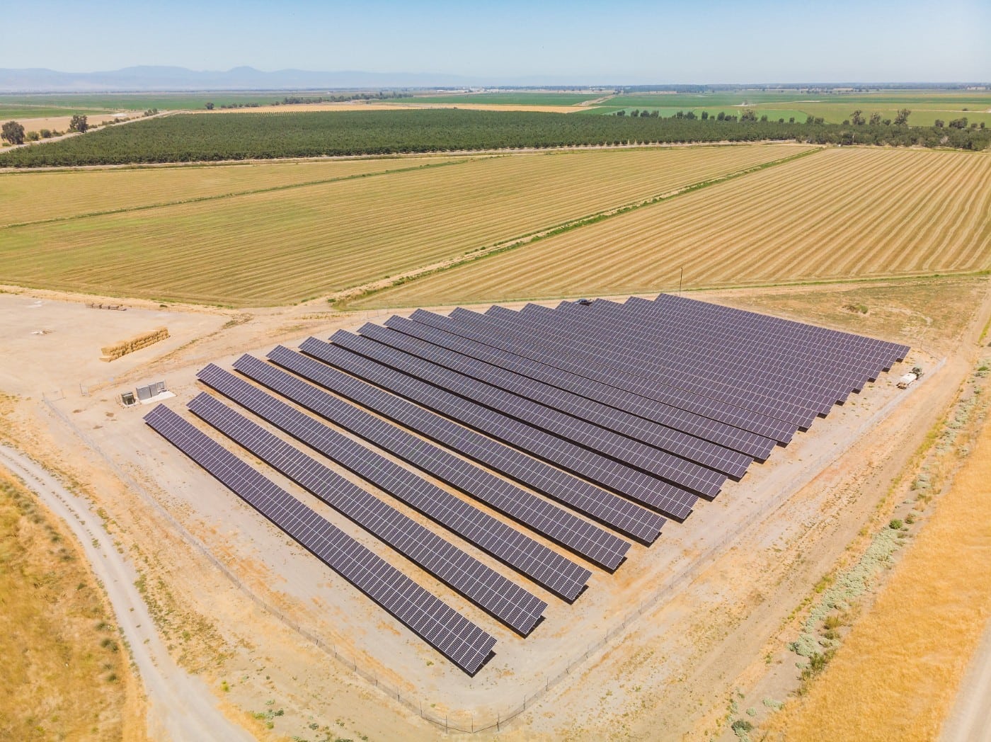 Aerial view of the solar farm constructed at Sycamore Mutual Water Company surrounded by green crop fields and cut wheat fields.