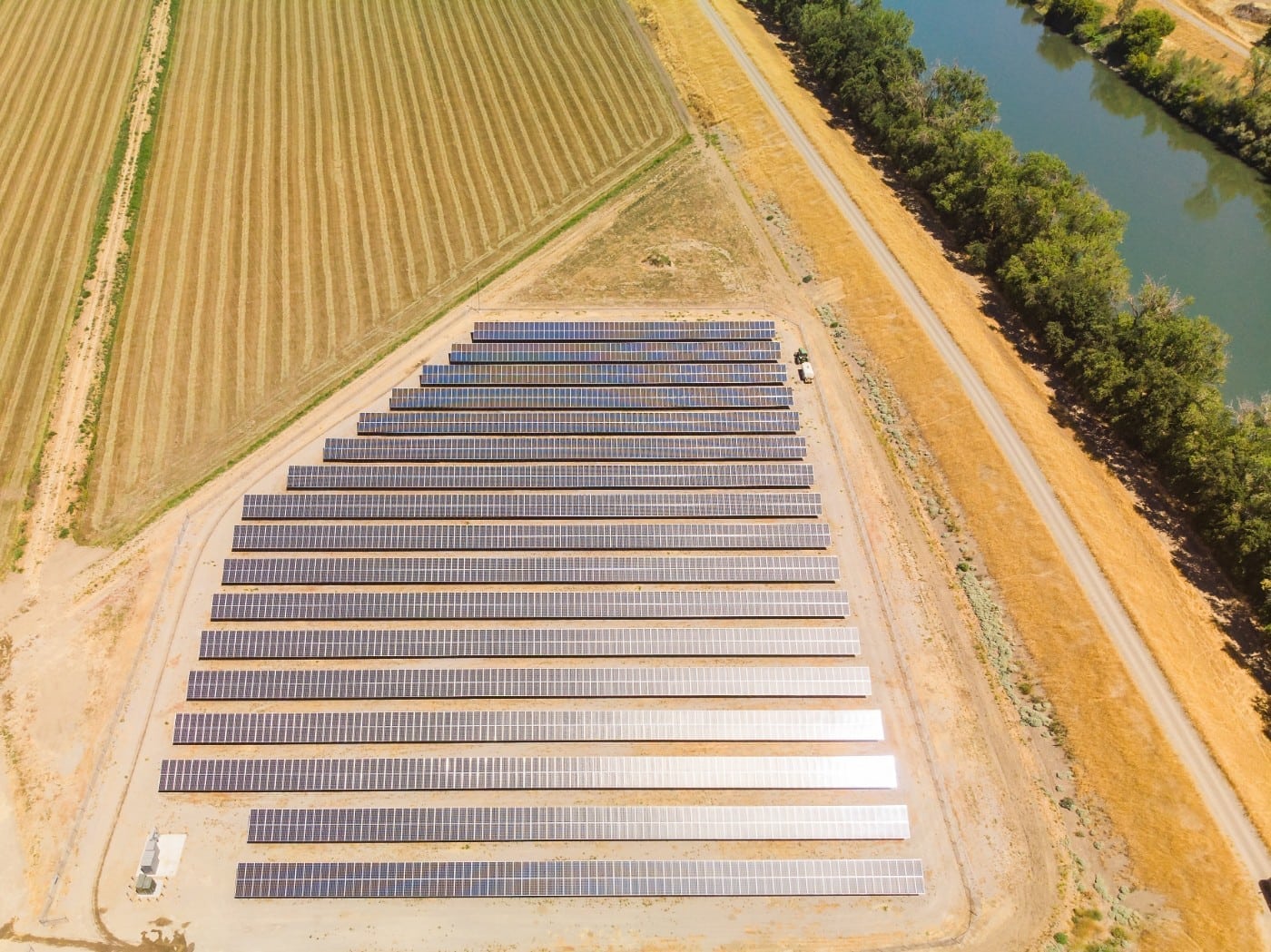Aerial view of the solar farm constructed at Sycamore Mutual Water Company with a river on the right and cut grass fields on the left.