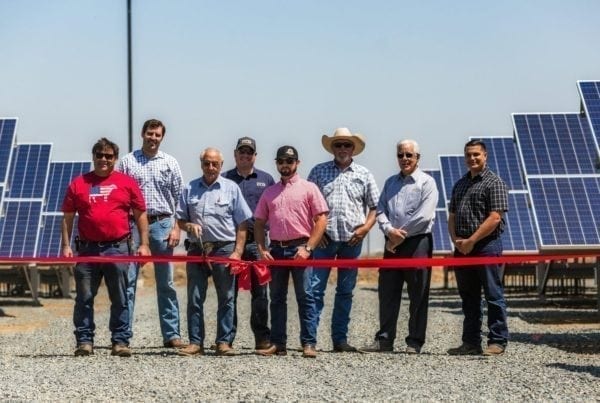A group of employees from Joe Simoes Dairy in Tipton, California standing at the ribbon cutting ceremony in front of their new solar system.