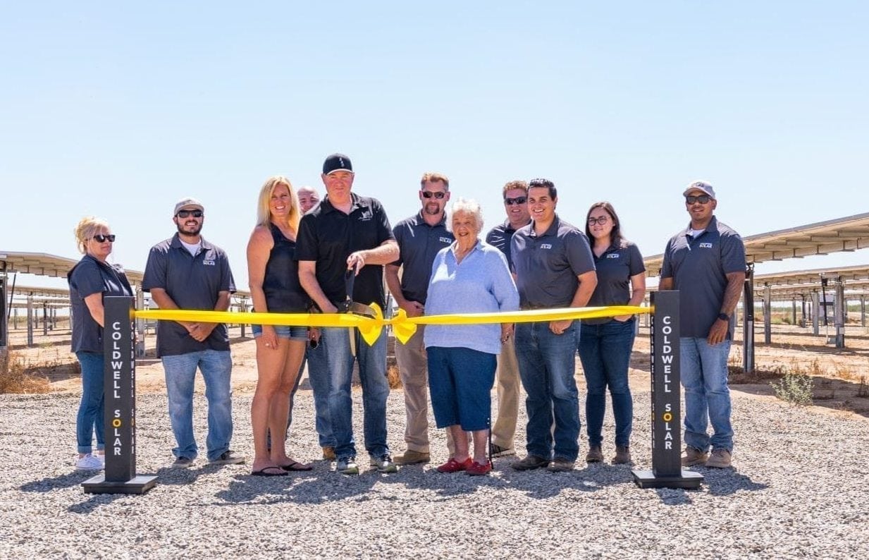A group of employees from Faust Family Dairy in Chowchilla, California standing at the ribbon cutting ceremony in front of their new solar system.