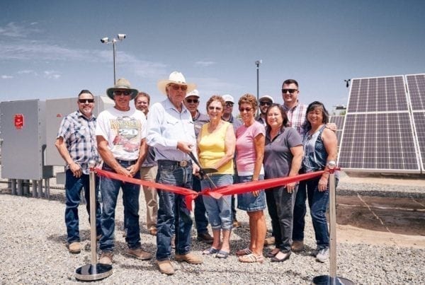 A group of employees from Hanse Farms in Hanford, California standing at the ribbon cutting ceremony in front of their new solar panels.