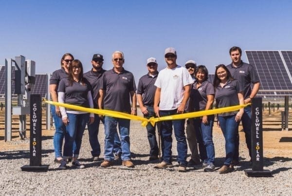 A group of employees from John Scheenstra Dairy in Wasco, California standing at the ribbon cutting ceremony in front of their new solar system.