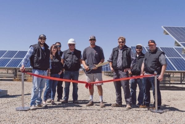 A group of employees from Rockshar Dairy in Merced, California standing at the ribbon cutting ceremony in front of their new solar system.