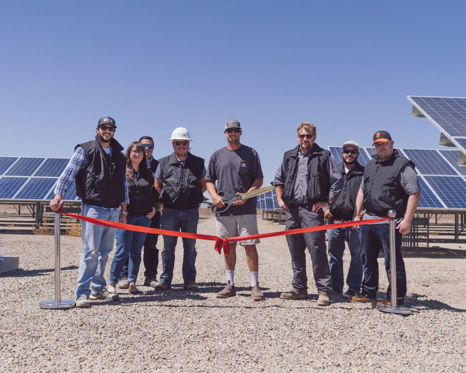 A group of employees from Rockshar Dairy in Merced, California standing at the ribbon cutting ceremony in front of their new solar system.