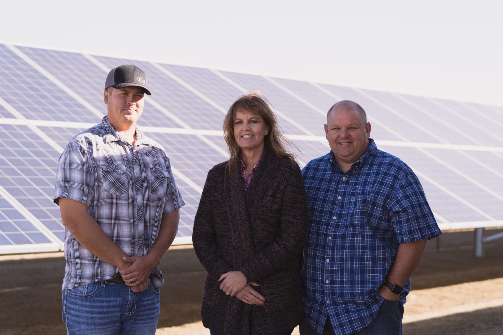 Three employees from Hammonds Ranch in Firebaugh, California standing in front of their solar panels.