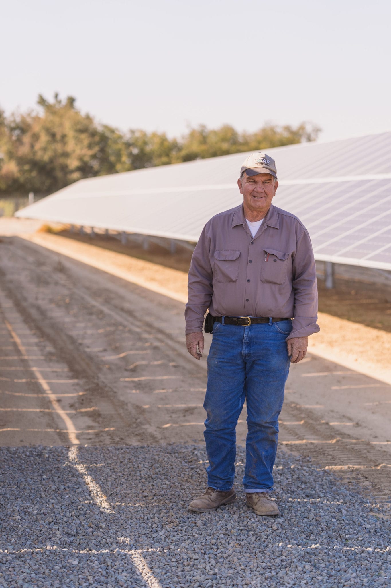 Farmer standing in front of a long row of solar panels at Dan Habib Ranch in Fresno, California.