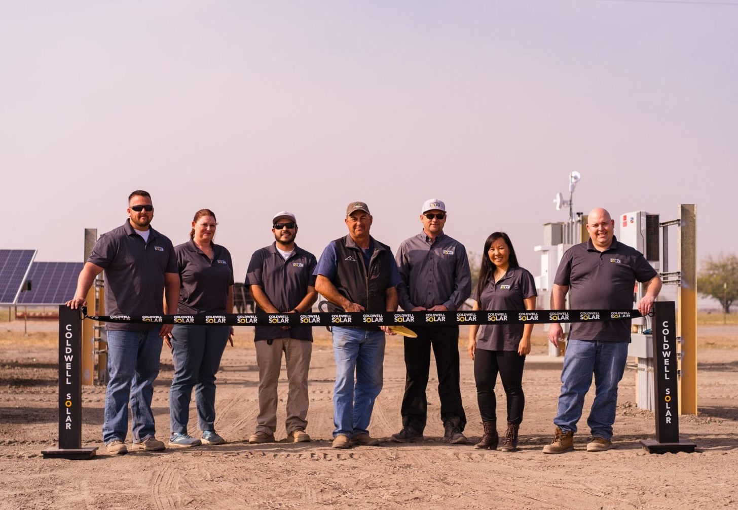 A group of people standing at the ribbon cutting ceremony of a new agricultural solar installation in Madera, California.