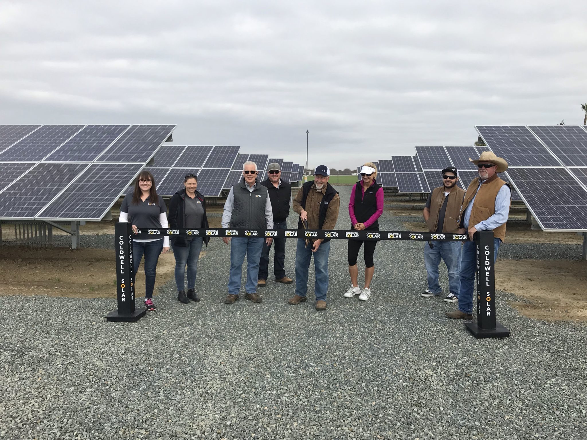 A group of people standing at the ribbon cutting ceremony in front of a newly constructed solar installation at Peter DeJong Dairy in Shafter, California.