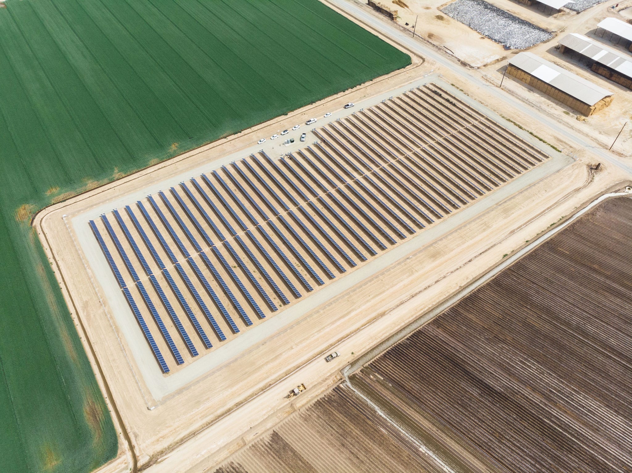 Aerial view of solar panels on a dairy farm surrounded by California agricultural land.