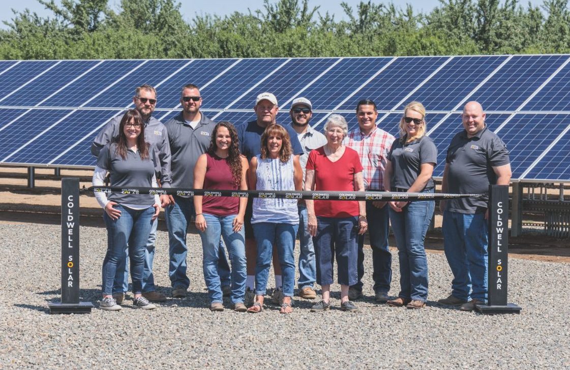 Employees of Machado Farms standing at the ribbon cutting ceremony in front of their new ground-mounted solar installation in Fresno.