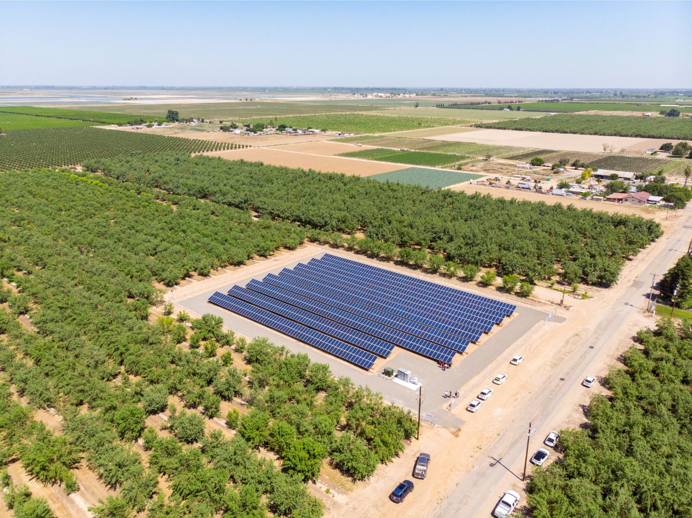 Aerial view of small solar farm at Machado Farms in Fresno surrounded by planted crop trees and farm land.