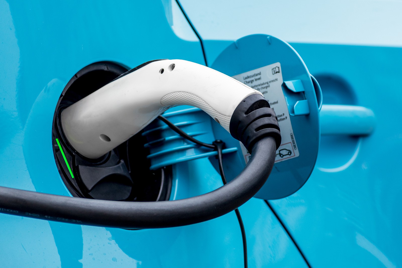 Closeup view of electric charger plugged into a blue vehicle.