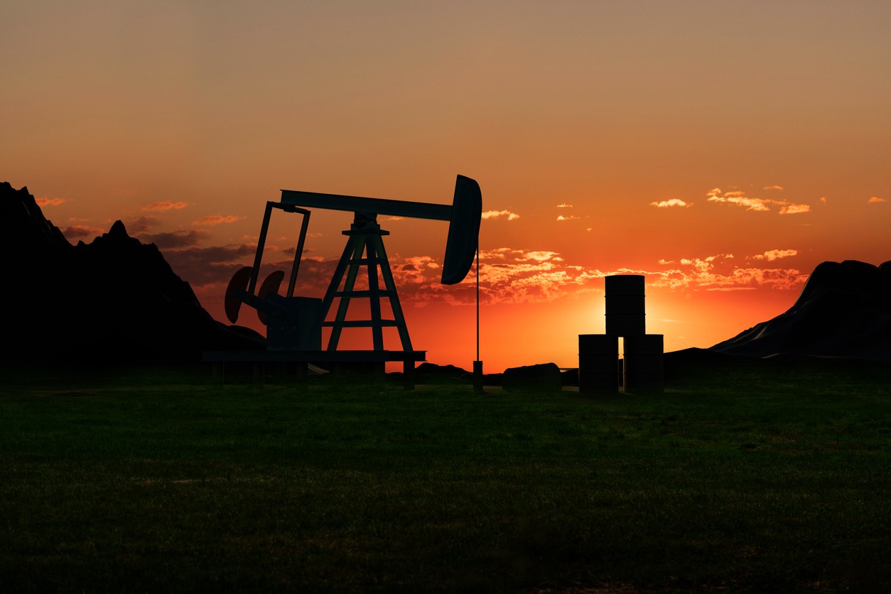 Lone oil drill in silhouette against an orange sunset.