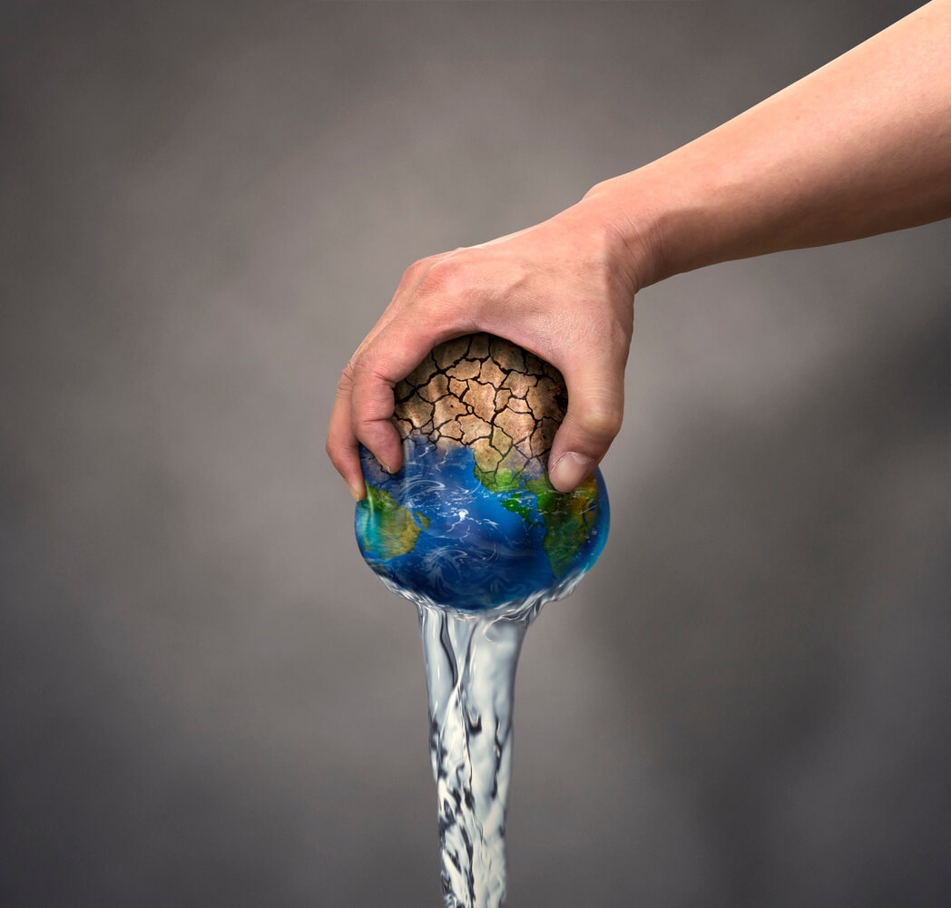 Concept of drought with a man's hand squeezing water from a ball that looks like the earth.