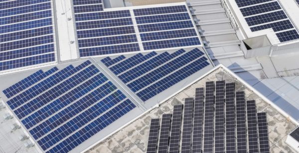Aerial view of various solar arrays on warehouse roofs. 