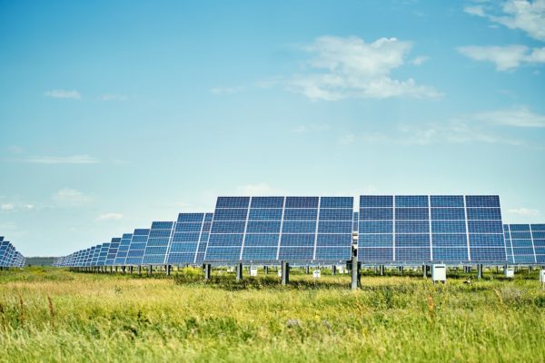 Solar farm in a field against a blue sky.
