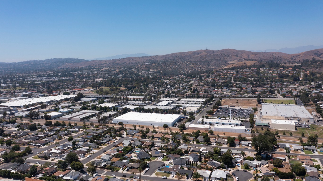 Aerial view of warehouses and buildings set among neighborhoods in the rolling hills of California.