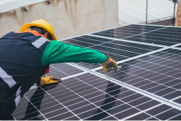 Worker performing maintenance on commercial solar panels. 
