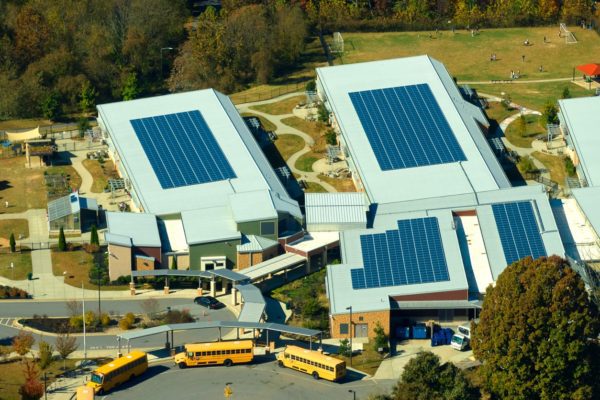 Aerial view of solar panels on modern school building roof. 