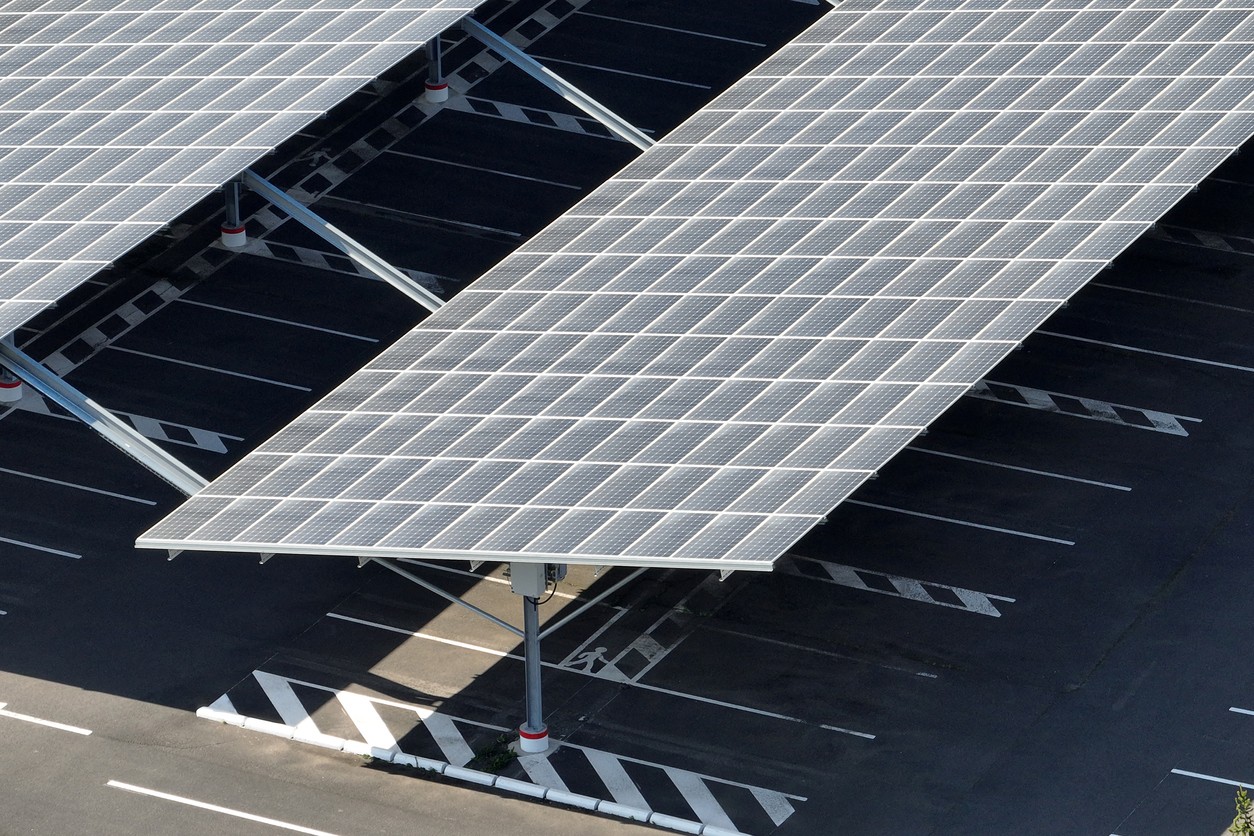 Aerial view of the solar panels on two rows of a solar carport with empty parking spaces underneath.