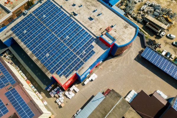 Aerial view of solar panel system on the roofs of two commercial buildings and a carport in the foreground.