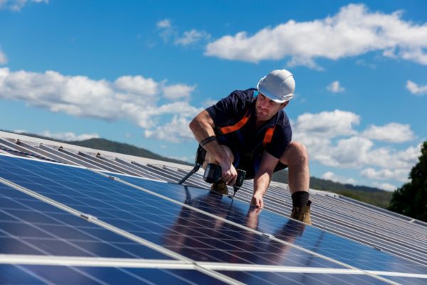 Man installing a ground-mounted commercial solar panel. 
