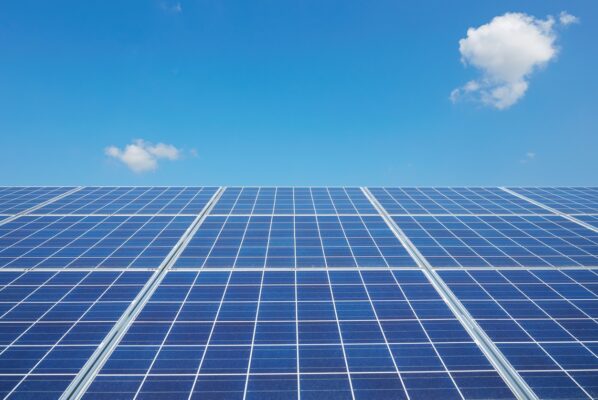 Closeup view of the squares on a blue polycrystalline commercial solar panel against a blue sky with a few clouds.