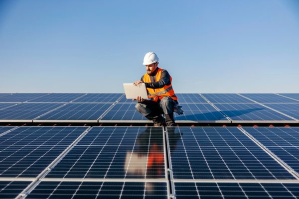 Worker checking solar panels on a roof.
