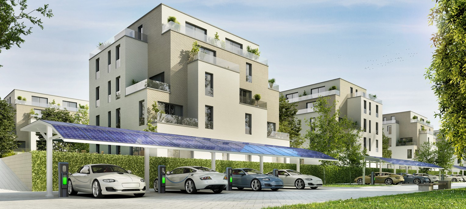 Luxury condominium complex and a long solar carport with cars parked underneath in front of it.