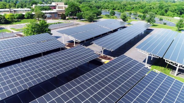Aerial view of the roofs of rows of commercial solar carports in a large parking lot. 